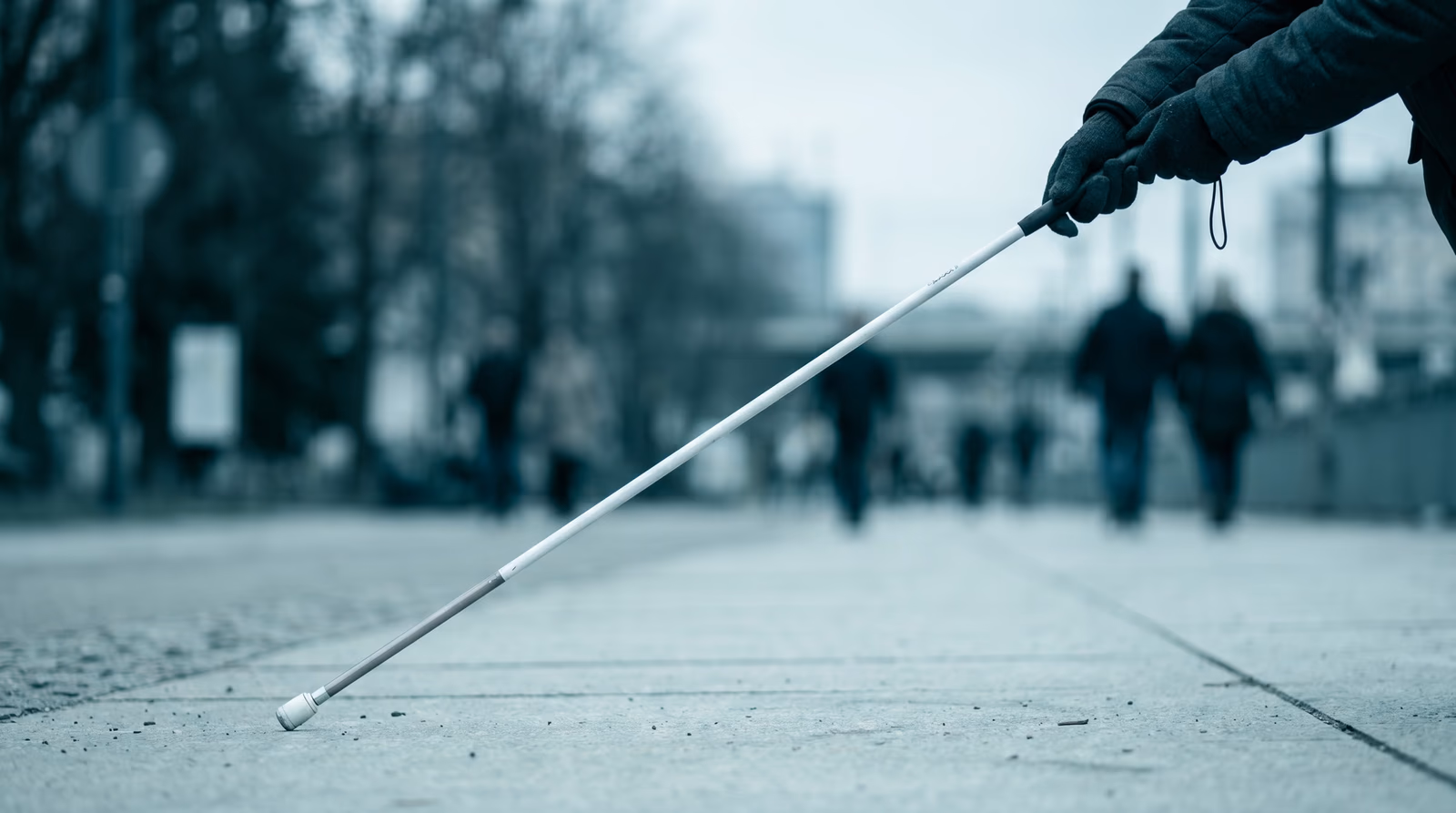 Close-up of hands using a white cane on a smooth pale pavement surface, representing web accessibility and inclusive design principles covered in WCAG guidelines