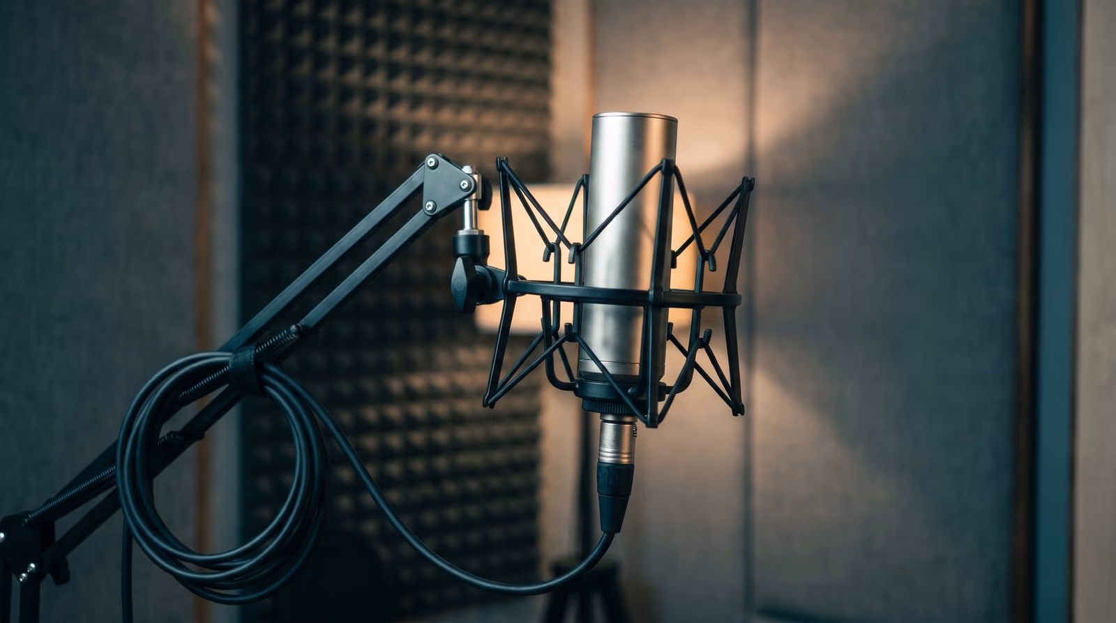 A sleek studio condenser microphone in cool teal light against a dark background with faint sound-wave ripples, representing brand voice and messaging