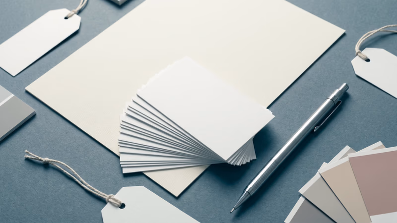 Blank business cards, letterhead, hang tags, and neutral color swatches arranged on a slate surface — representing the foundational elements of brand identity before design begins