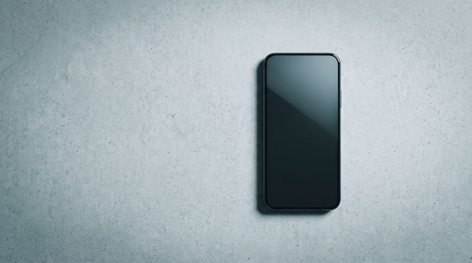 Single modern smartphone lying face-up on a pale concrete surface, photographed from above, representing mobile-first website design and optimization