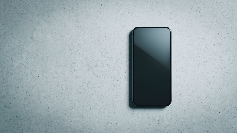 Single modern smartphone lying face-up on a pale concrete surface, photographed from above, representing mobile-first website design and optimization