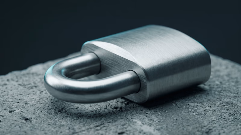 Brushed steel padlock closed on a raw concrete surface with cool teal rim lighting, representing website security essentials including SSL certificates and protection for small business sites