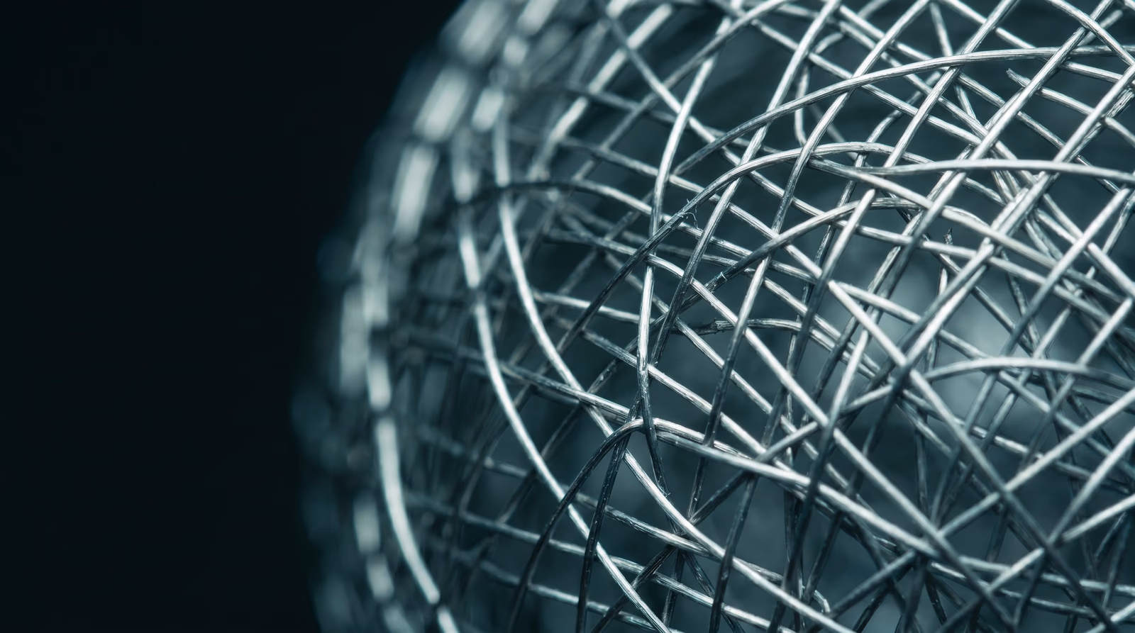Close-up of a fine metallic wire mesh illuminated by cool teal directional light, representing the structural and technical foundations of search engine optimization