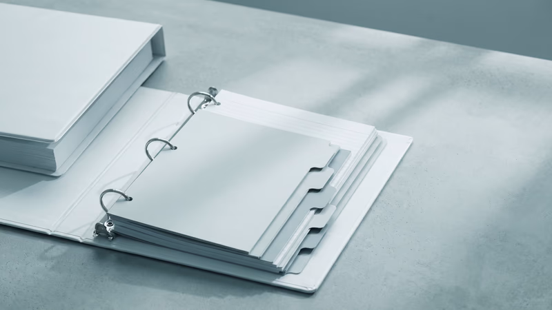 An open ring binder with neatly organized blank tabbed dividers and plain cards, representing design system documentation structure and governance organization