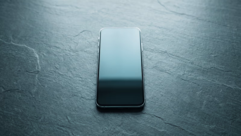 Single modern smartphone in flat-lay with a blank dark screen on a slate surface and generous negative space, representing a mobile-first design philosophy approach