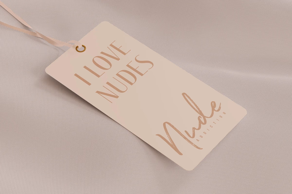 Nude Addiction garment label mockup designed by Desque, showing the wordmark on a warm neutral fabric tag