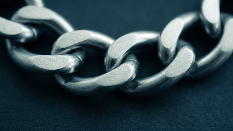 Interlocking brushed-steel chain links under cool directional lighting, representing the interconnected nature of link building and SEO authority