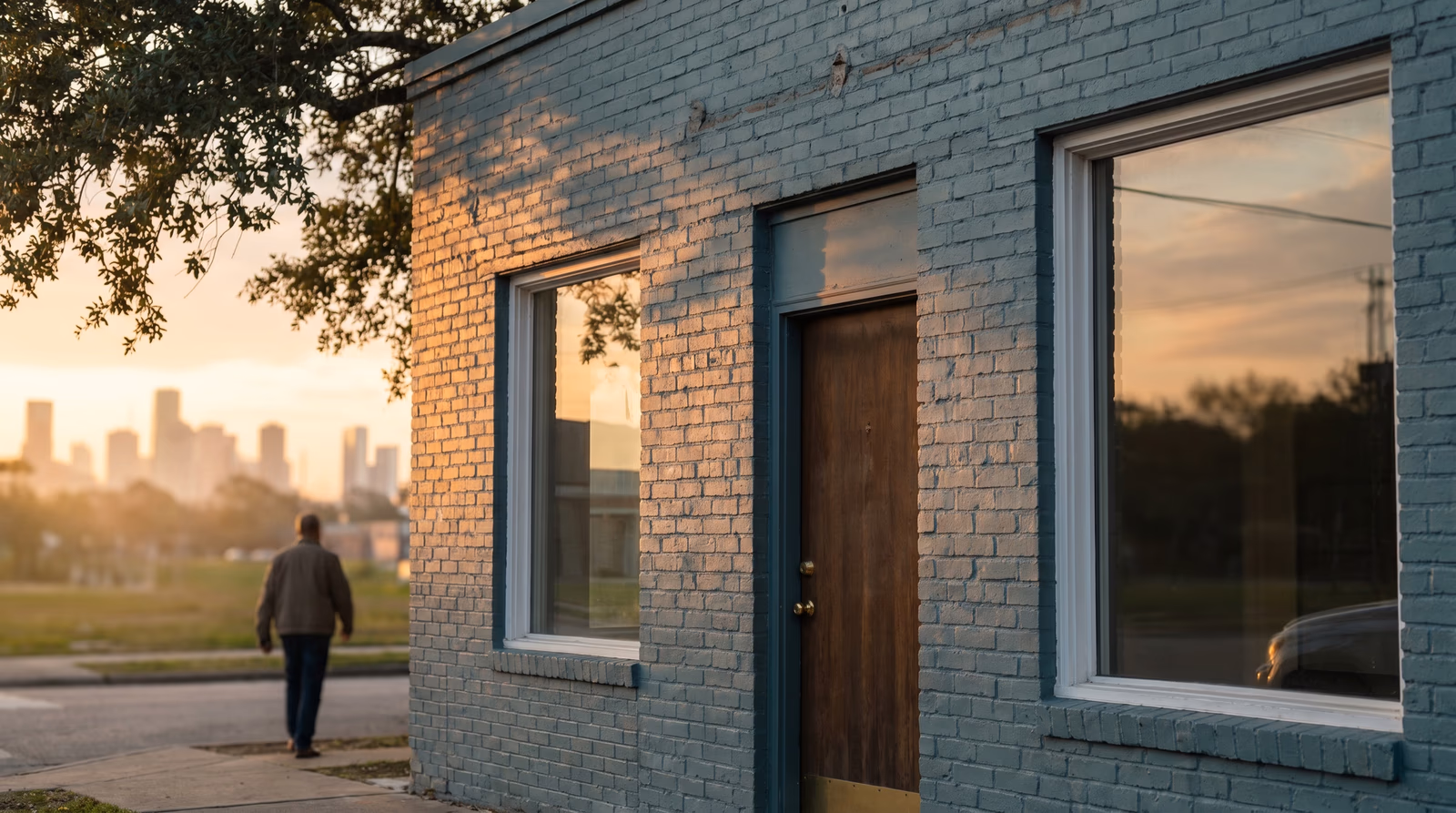 A small Houston business storefront at golden hour with a faint downtown skyline in the background, representing the importance of a professional web presence for local Houston businesses